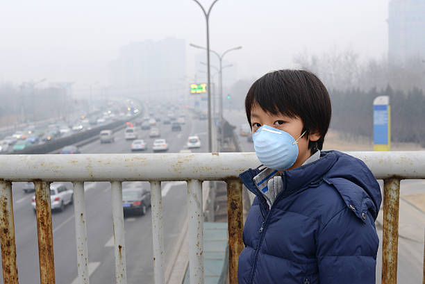 Asian child protects himself against air pollution by wearing mouth mask